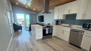 Eine moderne Küche mit Holzböden, weißen Schränken, einem eingebauten Backofen und einem Edelstahl-Geschirrspüler.