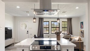 Una cocina moderna con una isla central, horno integrado y electrodomésticos de acero inoxidable.