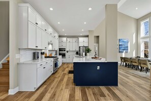 A modern kitchen with white cabinets, a central island, and a dining area with a view.