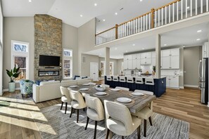 A spacious living area with a fireplace, a dining table set for six, and a kitchen with white cabinets.