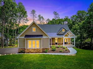 A two-story house with a stone foundation, a covered porch, and a well-maintained lawn.