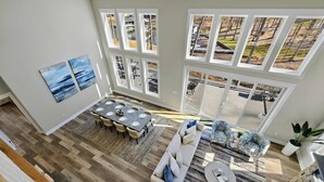 Ein geräumiger Wohnbereich mit Esstisch, Sofa und großen Fenstern mit Blick auf eine Terrasse.