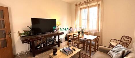 Una sala de estar con televisión, mesa de comedor y sofá.