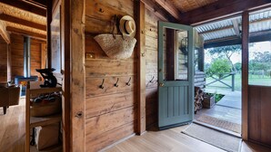 Un intérieur en bois avec une cheminée, une porte donnant sur l’extérieur et un panier accroché au mur.