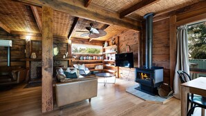 Un intérieur de chalet chaleureux avec une cheminée, un canapé en cuir, des étagères et un téléviseur.