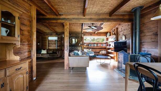 L’intérieur d’un chalet en bois comprend un coin repas, un salon avec une cheminée et une bibliothèque.