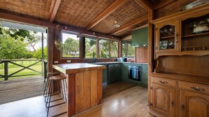 Une cuisine en bois dotée d’un coin bar, de grandes fenêtres et offrant une vue sur l’extérieur.
