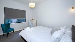 A bedroom with a bed, a chair, a bedside table, and a window with a view. - 4BR Pet friendly home with ocean views (Kiama)