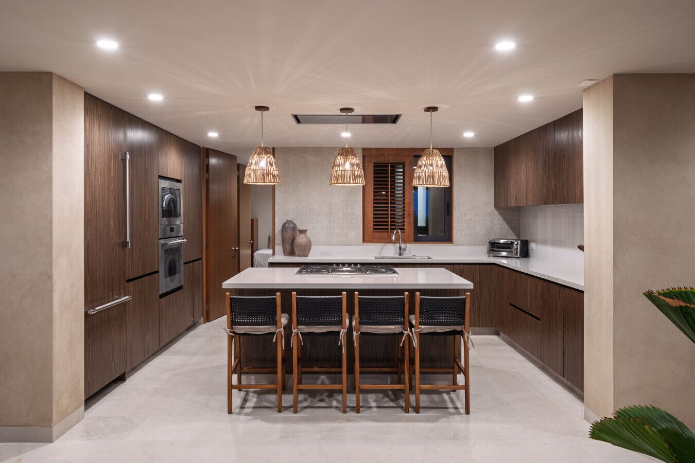 A modern kitchen with a central island, wooden cabinets, stainless steel appliances, and pendant lighting.