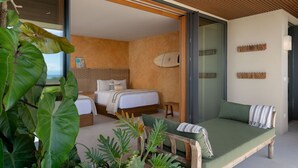 Een moderne slaapkamer met een bed, een groene bank en uitzicht op de oceaan.