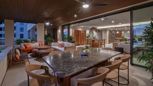 Een modern interieur met een eethoek, banken en een grote glazen deur naar buiten.