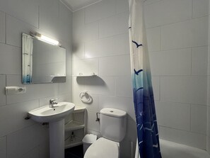 A bathroom with a sink, mirror, toilet, and shower curtain. - Apartment 1 minute from Riells Beach (l'Escala)
