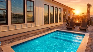 Una piscina con zona solarium, ampie finestre e vista sul tramonto.