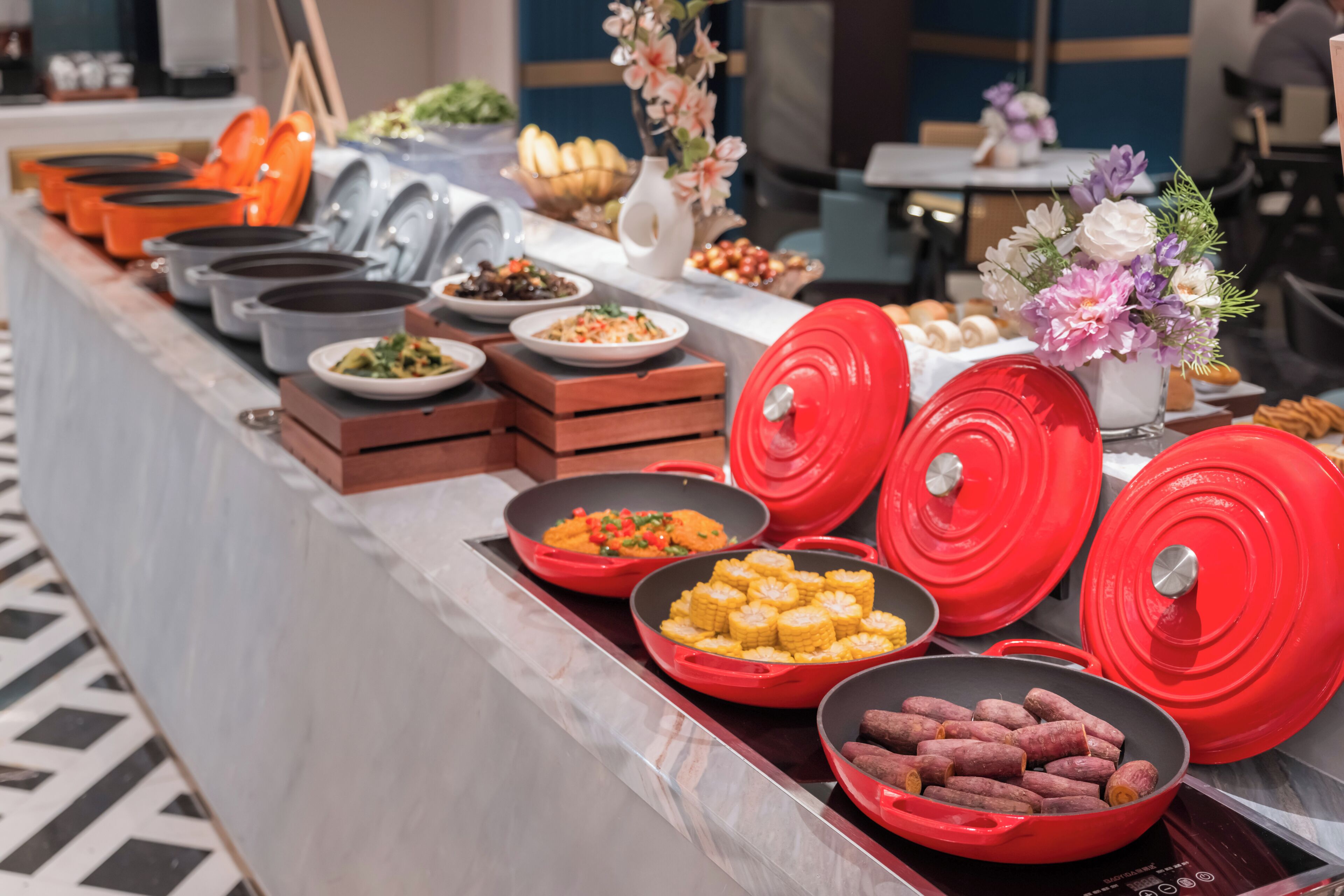 Un buffet proposant une variété de plats et de récipients, notamment des pots, des bols et des plateaux rouges et gris.