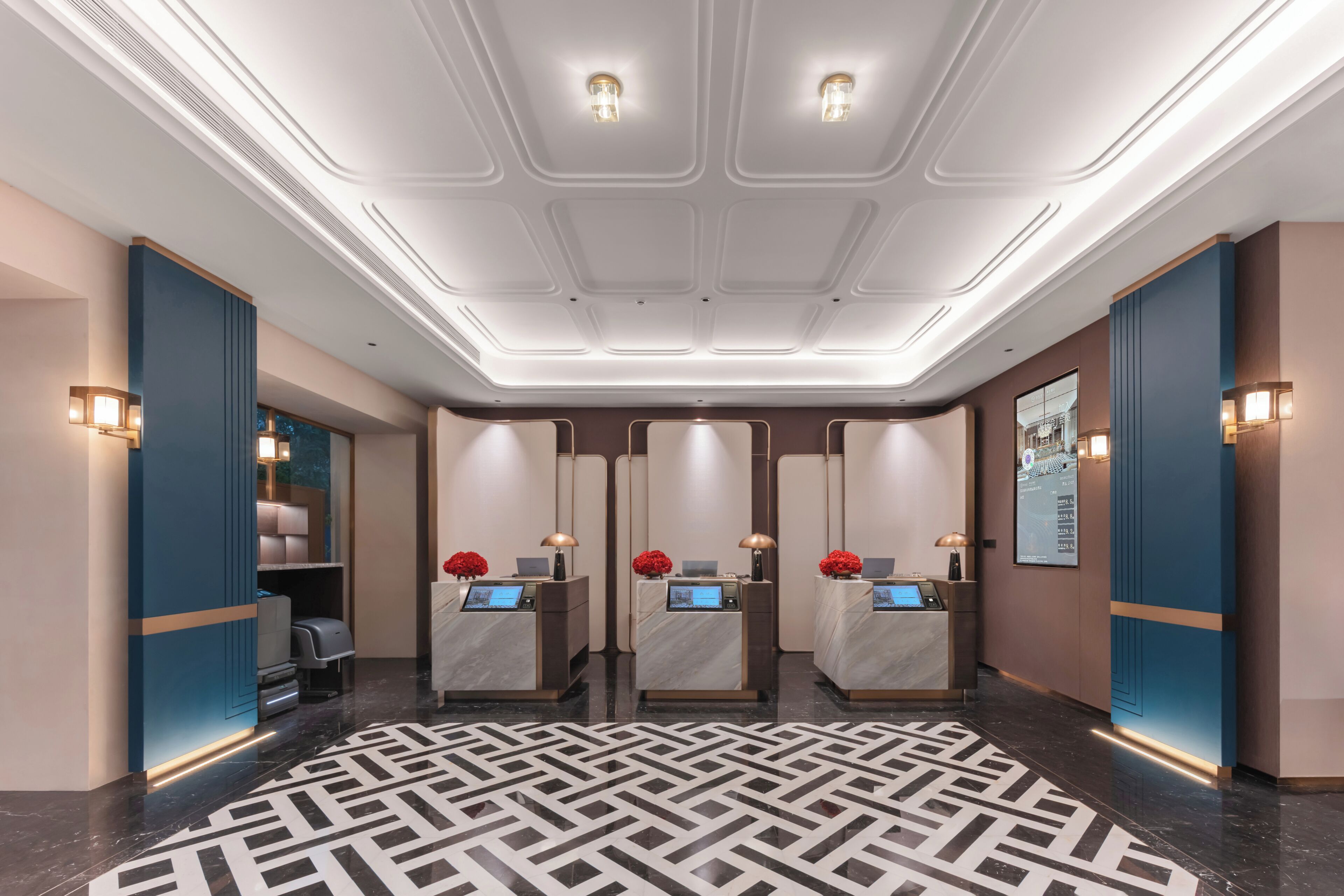 A hotel lobby with a reception desk, seating area, and a patterned floor.