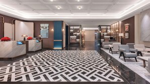 Una moderna hall di hotel con scrivania della reception, zona salotto e pavimento a motivi.
