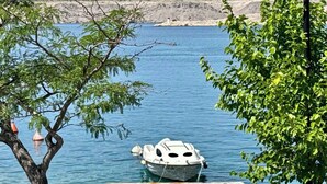 Un barco amarrado en un muelle, con agua cristalina y una costa rocosa al fondo.