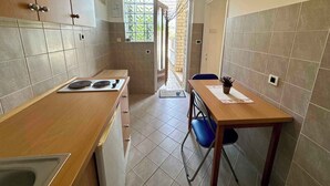Una cocina compacta con estufa, armarios y un comedor con sillas.