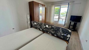 Una habitación con una cama, un armario, un ventilador de techo, un mueble para televisión y una ventana con vistas.
