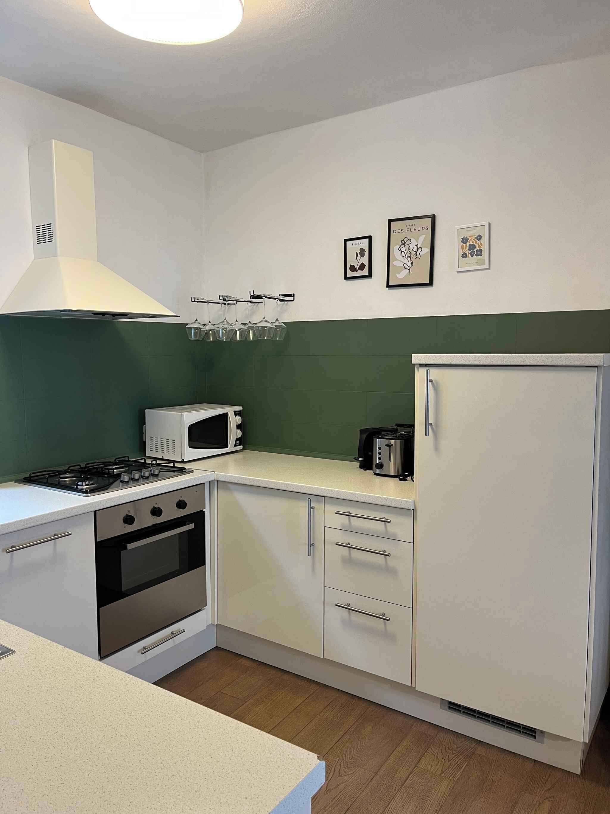 Een kleine keuken met een gasfornuis, oven, magnetron en een koelkast.