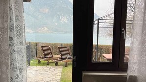 Ein Zimmer mit Blick auf einen See und Berge, eine Holzbank, eine Heizung und eine Tür mit Vorhang.