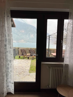 Ein Zimmer mit Blick auf einen See und Berge, eine Holzbank, eine Heizung und eine Tür mit Vorhang.