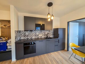 A modern kitchen with dark cabinetry, a patterned backsplash, and a built-in oven. - Stylish single apartments in Jenbach (Jenbach)