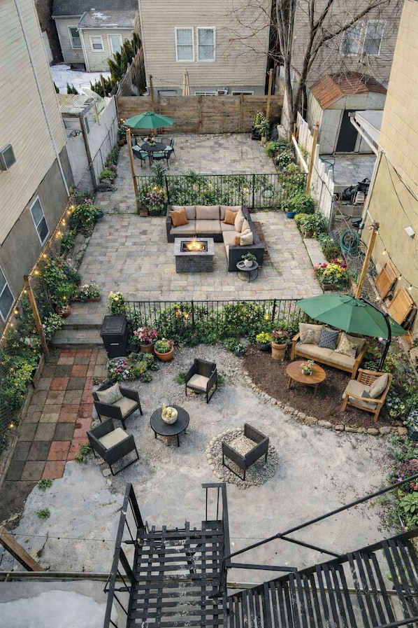 A courtyard with outdoor seating, a fire pit, and potted plants.