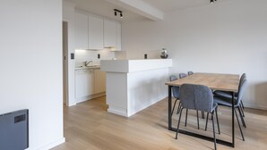 Eine moderne Küche mit weißen Schränken, einem Holzespeisetisch und grauen Stühlen.