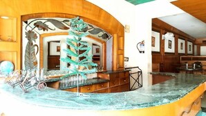 A bar area with a green artificial tree, a marble counter, and wooden paneling. - HOTEL INTERNATIONAL (Jalandhar)