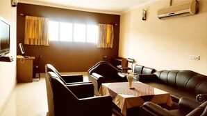 A room with a sofa, a table with a vase, a TV, and an air conditioner. - HOTEL INTERNATIONAL (Jalandhar)