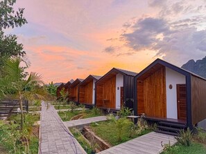 Un hilera de cabañas de madera con un sendero que las conecta, rodeado de vegetación.