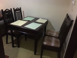 A dining table with four chairs, a bench, and a wall-mounted shelf. - 2BR 1BA apartment near Kitintale Market Kampala with Wi-Fi, AC (Kampala)