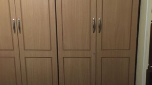 Een slaapkamer met een bed, nachtkastje en een garderobe met drie deuren.