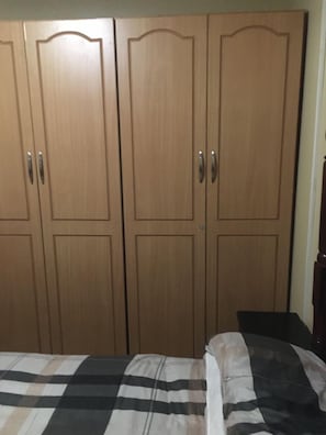 Ein Schlafzimmer mit einem Bett, einem Nachttisch und einem dreitürigen Kleiderschrank.