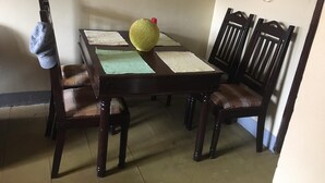 Een eettafel met vier stoelen, een gele bal en een witte tafelkleed.