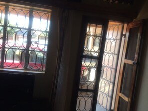 A room with a barred window and a door, a radiator, and a view of a street with parked cars. - 2BR 1BA apartment near Kitintale Market Kampala with Wi-Fi, AC (Kampala)