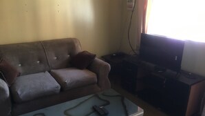 Een woonkamer met een bank, een salontafel, een tv-meubel en een televisie.