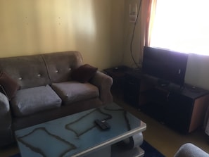 Ein Wohnzimmer mit einer Couch, einem Couchtisch, einer TV-Konsole und einem Fernseher.