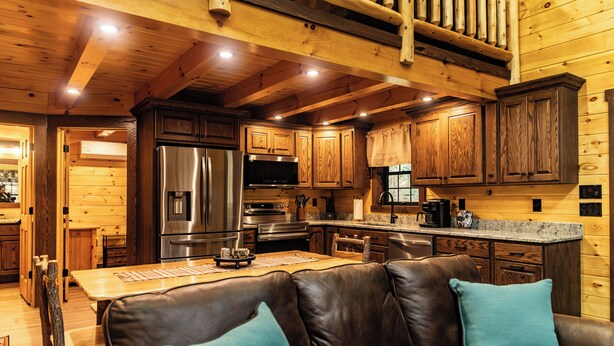 L’intérieur d’une cabane comprend une cuisine, un coin repas et un salon avec un canapé en cuir.