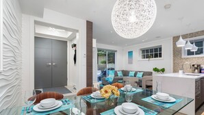 A modern dining area with a glass table, blue placemats, and white plates. - Kitsilano Retreat: Private 3-Bed w/ Parking & BBQ (Vancouver)