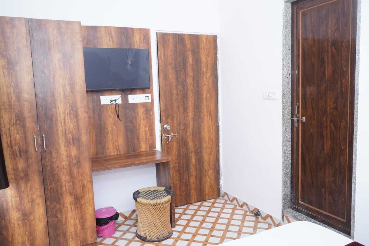 Une chambre avec une armoire, un téléviseur, une porte et une petite poubelle.