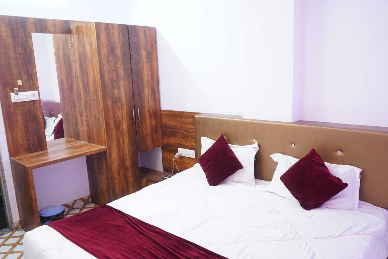 A bedroom with a bed, a wooden wardrobe, and a mirror.