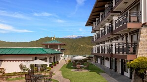 A hotel courtyard with outdoor seating, a stone pathway, and a view of mountains. - Welcomhotel By ITC Hotel Denzong Regency (Gangtok)