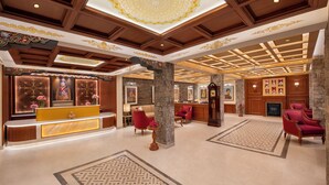 A lobby with a reception desk, seating area, decorative ceiling, and stone pillars. - Welcomhotel By ITC Hotel Denzong Regency (Gangtok)
