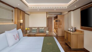 A hotel room with a large bed, a seating area, a TV, and a kitchenette. - Welcomhotel By ITC Hotel Denzong Regency (Gangtok)