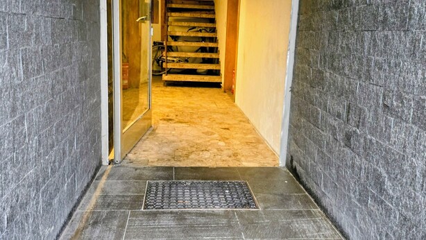 Un couloir étroit avec un escalier en bois menant à l’étage supérieur.