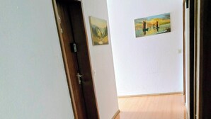 Un couloir doté d’un plancher en bois, d’une porte et de deux tableaux accrochés au mur.