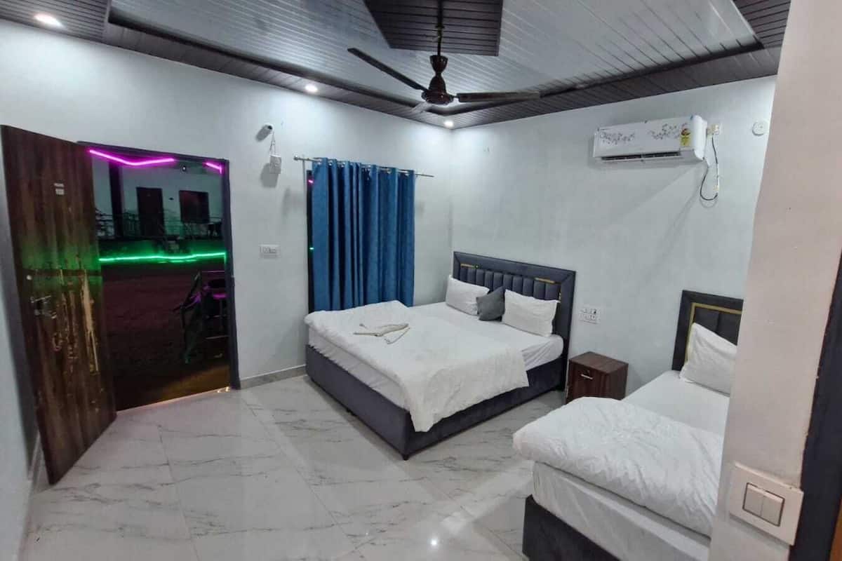 Un dormitorio con dos camas, ventilador de techo, unidad de aire acondicionado y vista al exterior.
