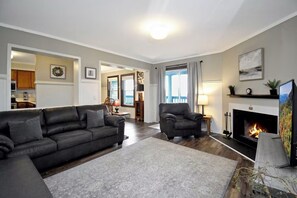 Een woonkamer met een open haard, een bank, een stoel en een televisie.